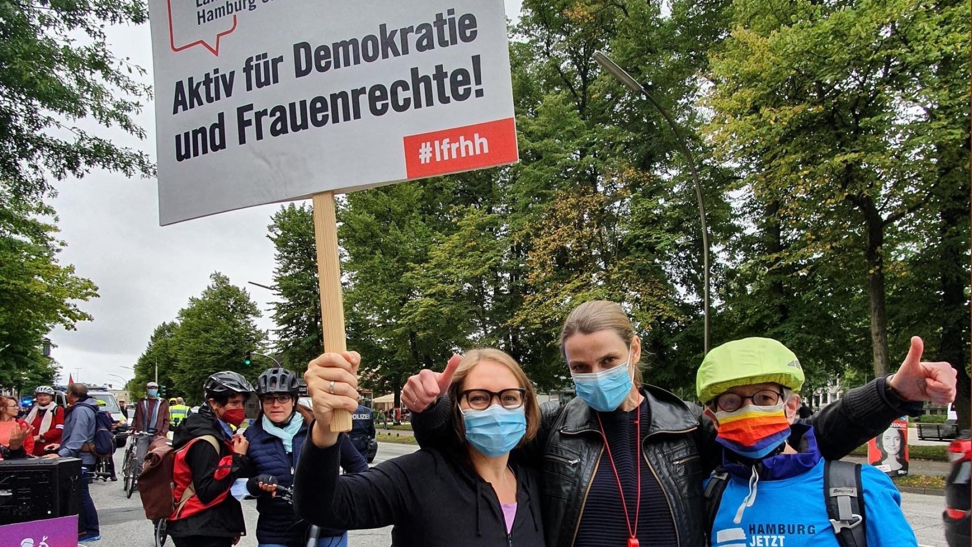 Vorständinnen des Landesfrauenrat Hamburg auf einer Demo des DGB halten ein Schild mit der Aufschrift "Aktiv für Demokratie und Frauenrechte"