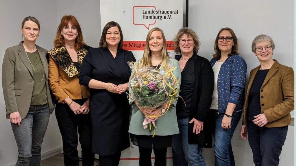 Annika Huisinga, Dr. Silke Martini, Katharina Fegebank, Dr. Dana-Sophia Valentiner, Petra Ackmann, Dr. Christina Maria Huber und Eva Burgdorf stehen vor dem Banner des Landesfrauenrat Hamburg.