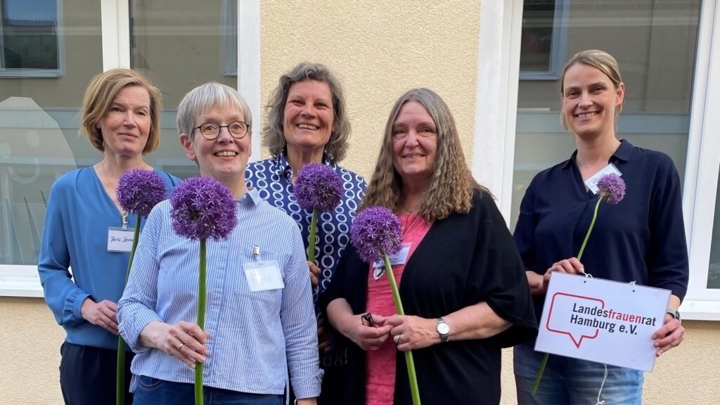 Doris Schramm, Eva Burgdorf, Angela Fechner, Angelika Ohse und Annika Huisinga posieren als Gruppe mit Blumen und einem Schild, auf dem „Landesfrauenrat Hamburg“ steht