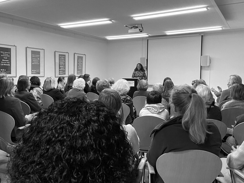 Ein gut gefüllter Raum beim Landesfrauenrat Hamburg, das Publikum applaudiert der Sprecherin.