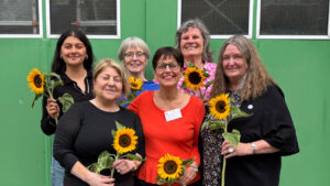 Zara Canbay, Güler Ulas, Eva Burgdorf, Jülide Sünter, Angela Fechner und Angelika Ohse posieren als Gruppe mit Sonnenblumen.